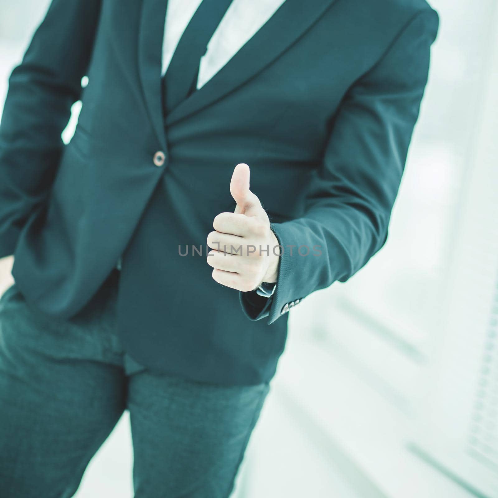 closeup of a successful businessman making a gesture - a thumbs up in the background of a large window