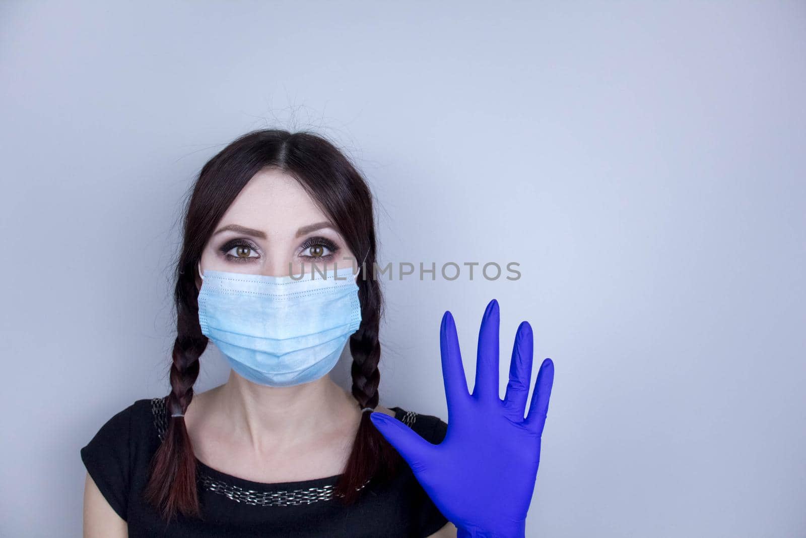 Woman wearing protection face mask against coronavirus. Woman in a mask looking shocked or worried with hand up. by JuliaDorian