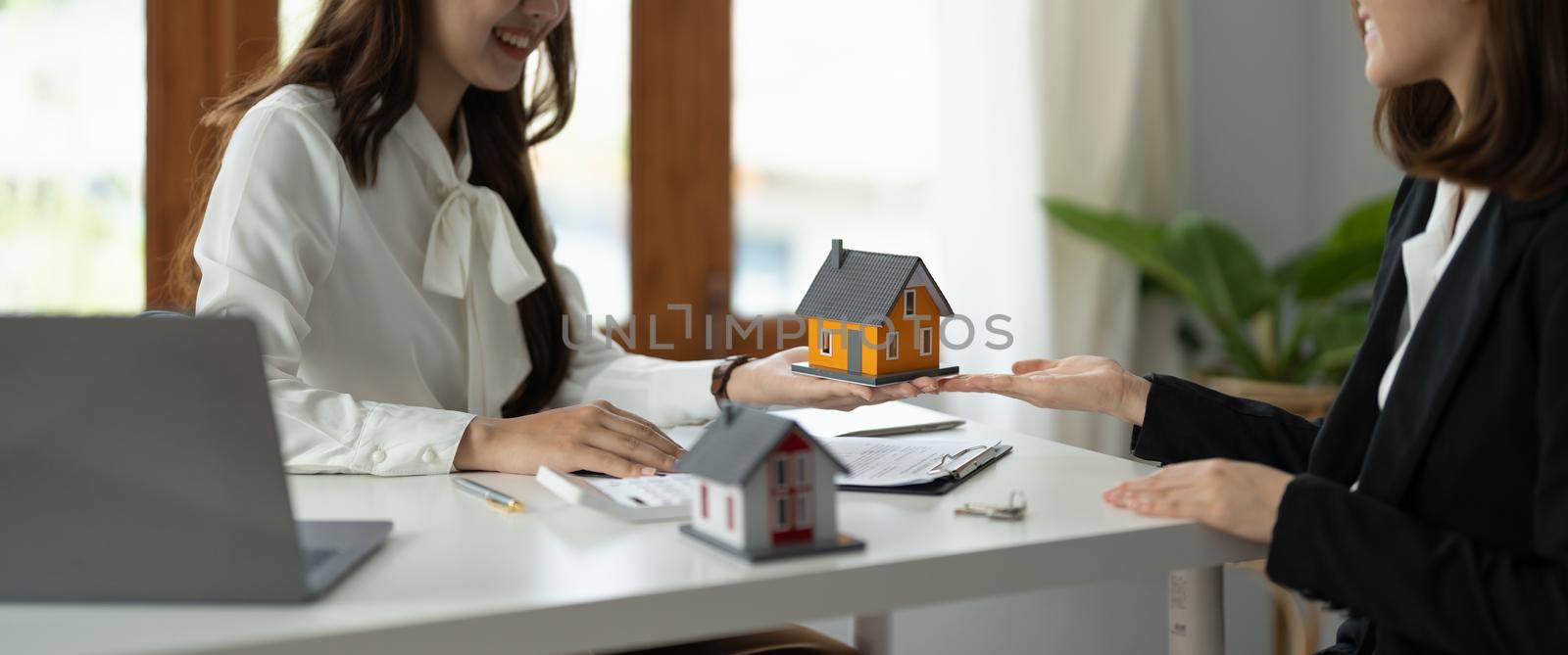 experienced real estate agent showing house model to client and ready to sign contract.