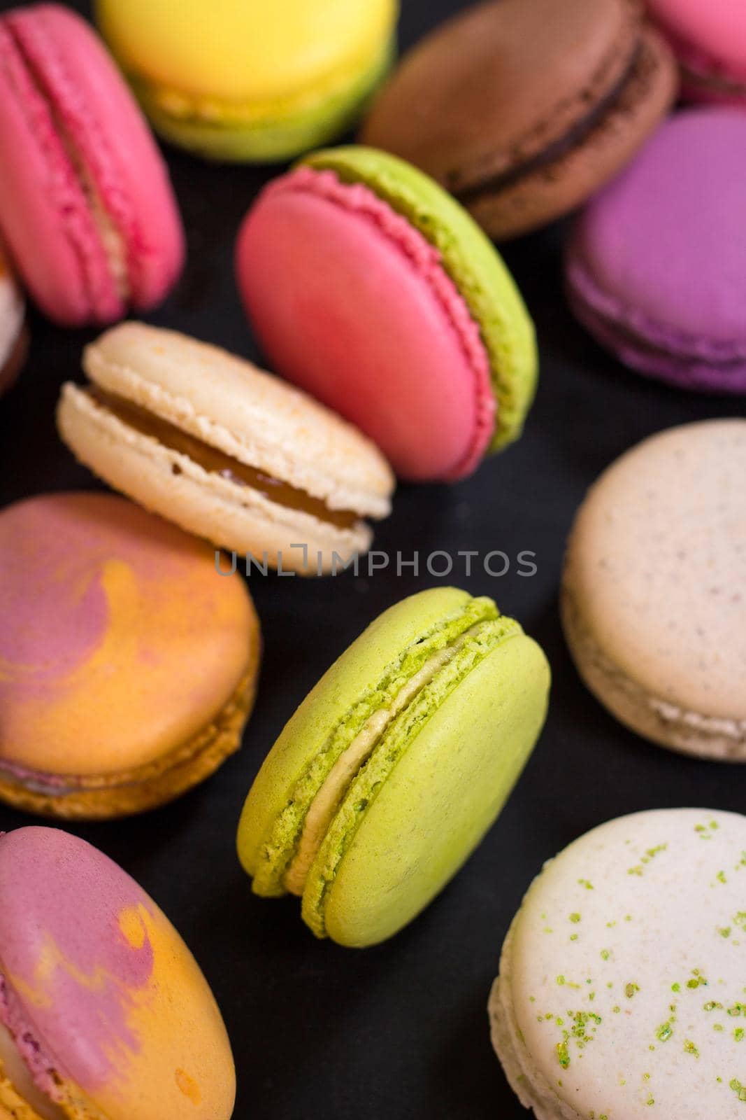 Assorted colorful french cookies macaroons on a dark background. Closeup. Concept of the macaroons