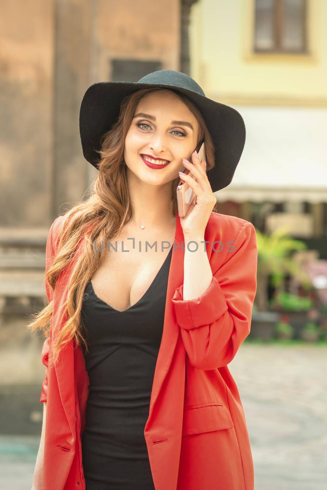 Young pretty woman is talking by the mobile phone wearing hat and smiling.