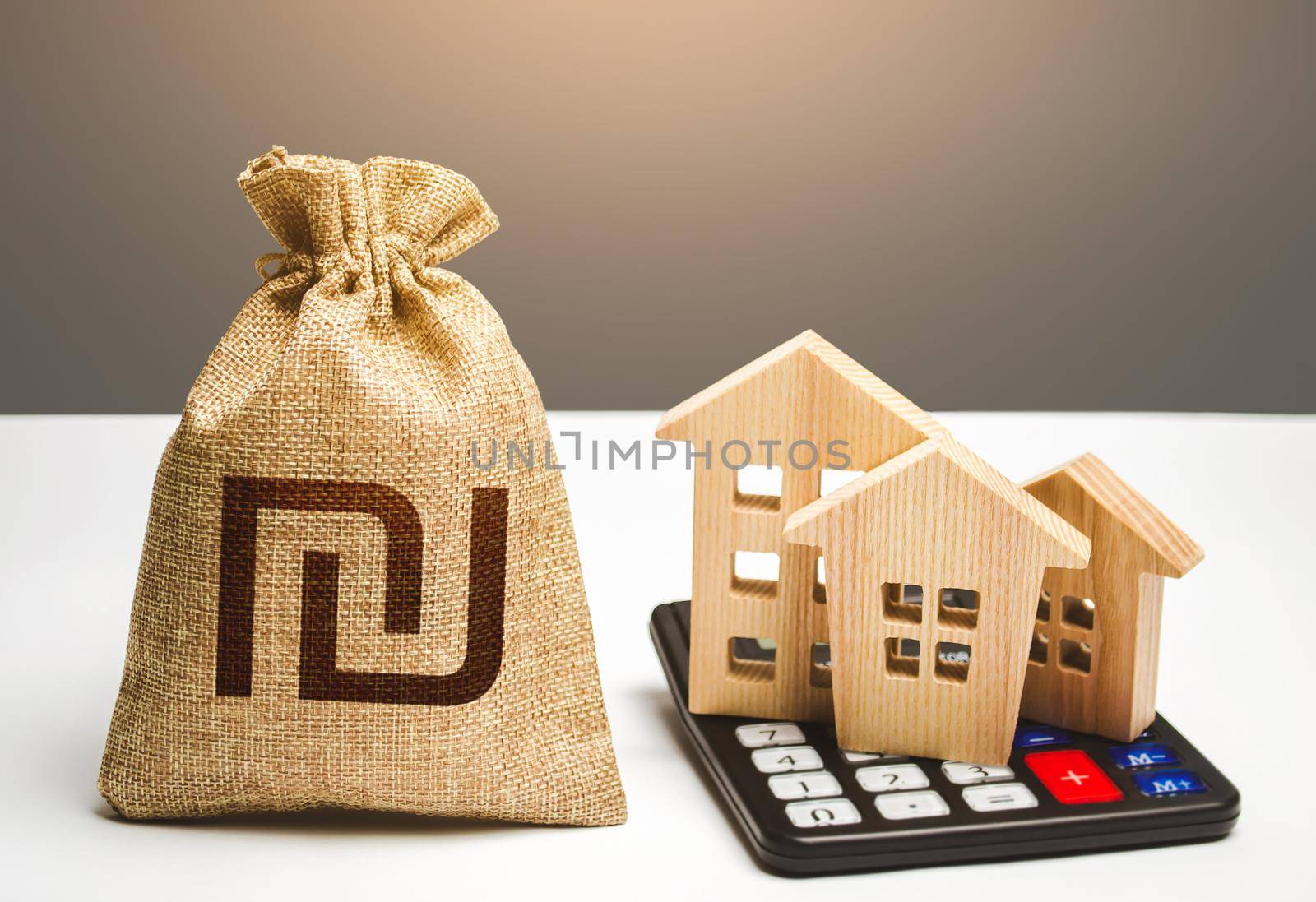 Houses on a calculator and israeli shekel money bag. Realty or rental business. Real estate valuation. Mortgage loan. Utilities and services expenses. Taxes. Buying and selling. Building maintenance.