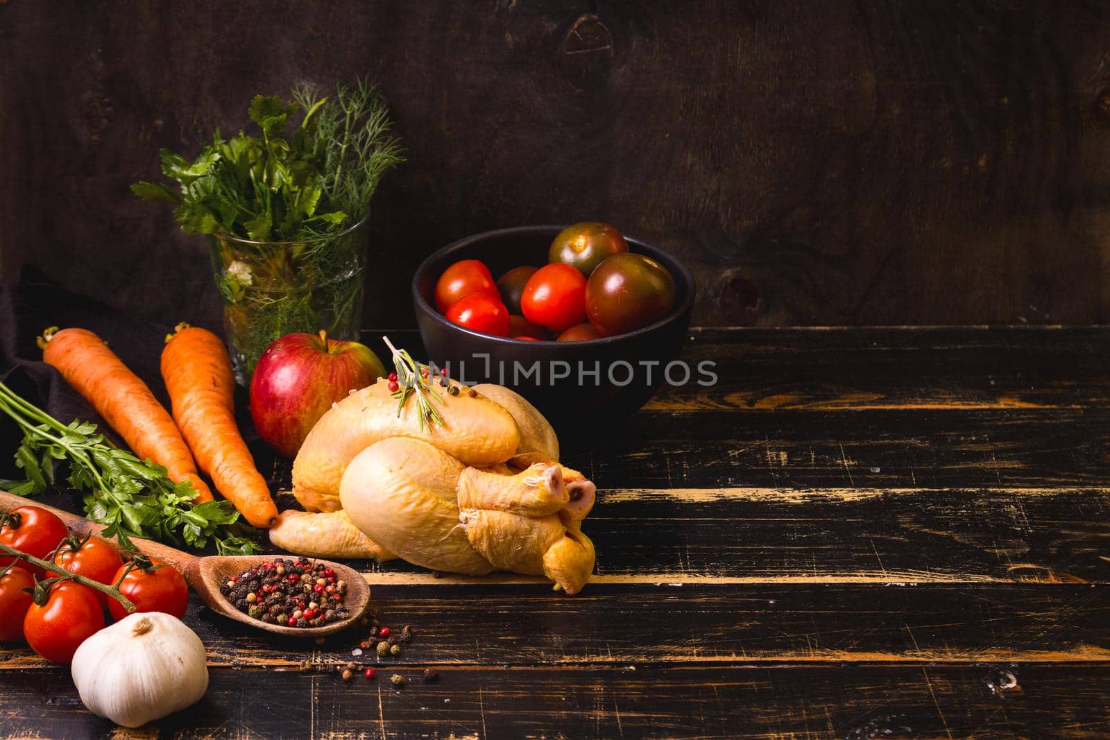 Raw whole chicken ready for cooking. Chicken, vegetables, herbs, spices on black rustic wooden background. Space for text. Food frame. Diet or healthy eating. Ingredients for cooking. Selective focus