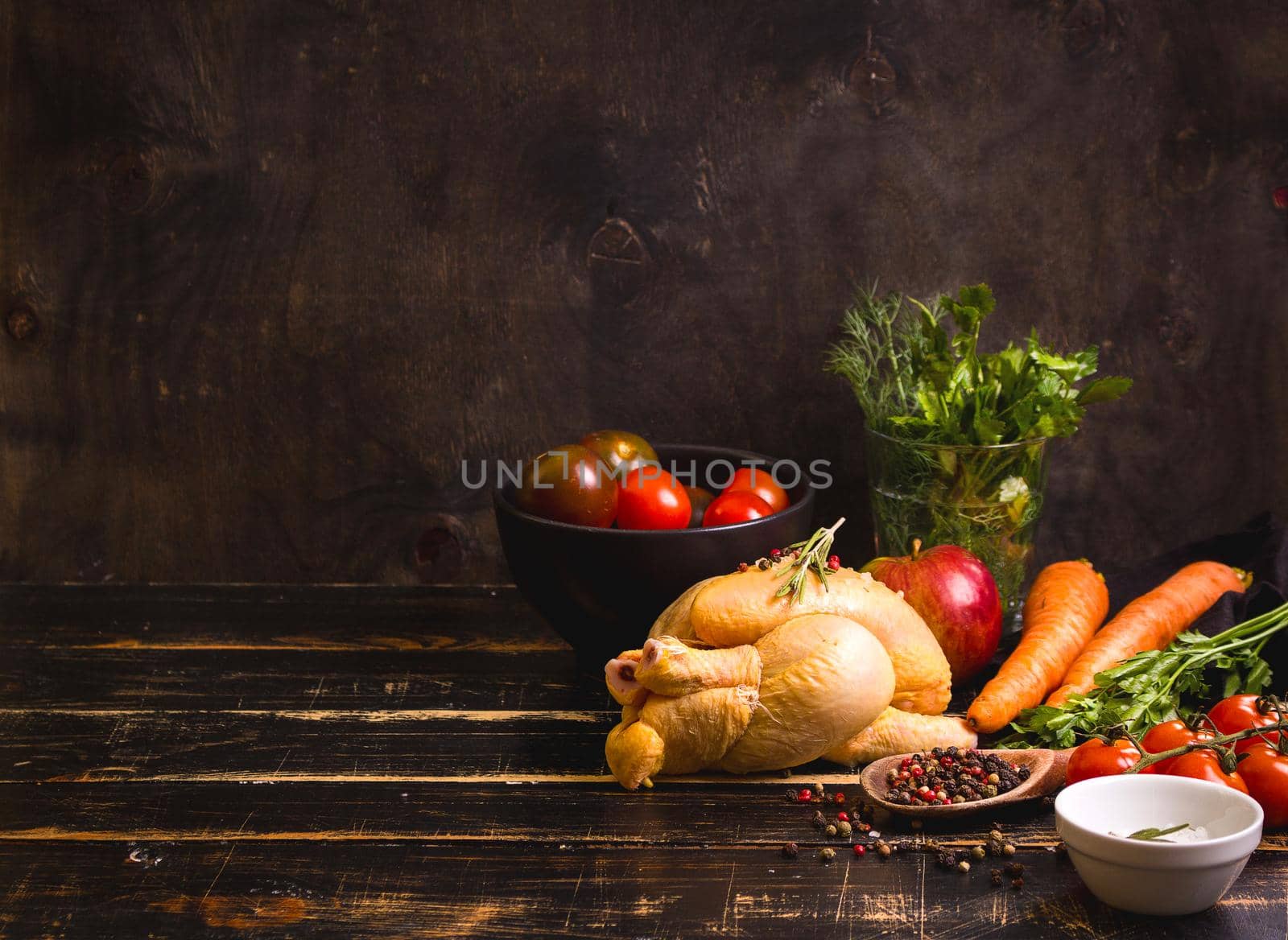 Raw whole chicken ready for cooking. Chicken, vegetables, herbs, spices on black rustic wooden background. Space for text. Food frame. Diet or healthy eating. Ingredients for cooking. Selective focus