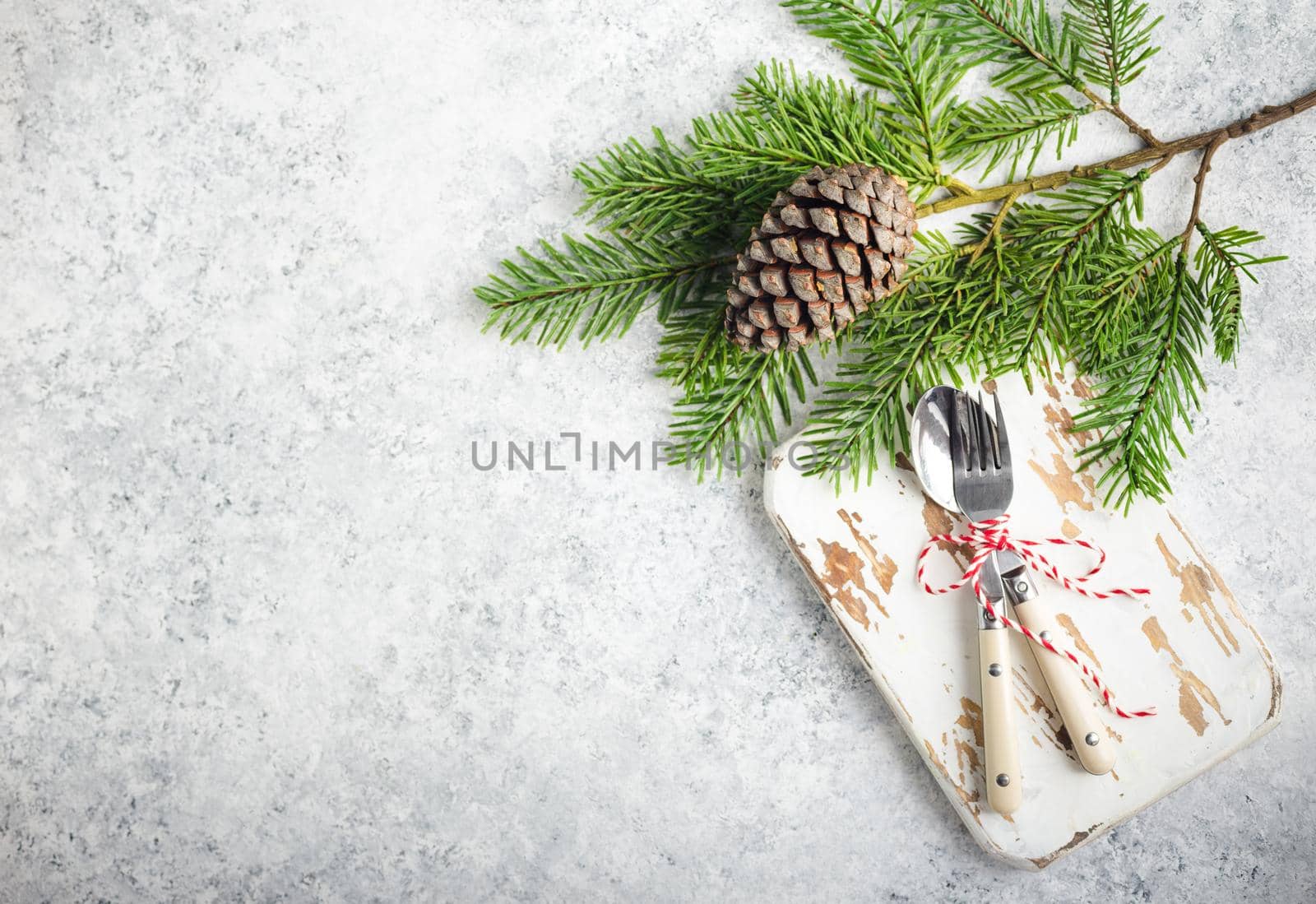 Christmas/New Year background. Christmas table place setting. Festive dinner background. Spoon, fork, fir branch on white concrete background. Christmas decoration. Space for text. Top view. Holidays