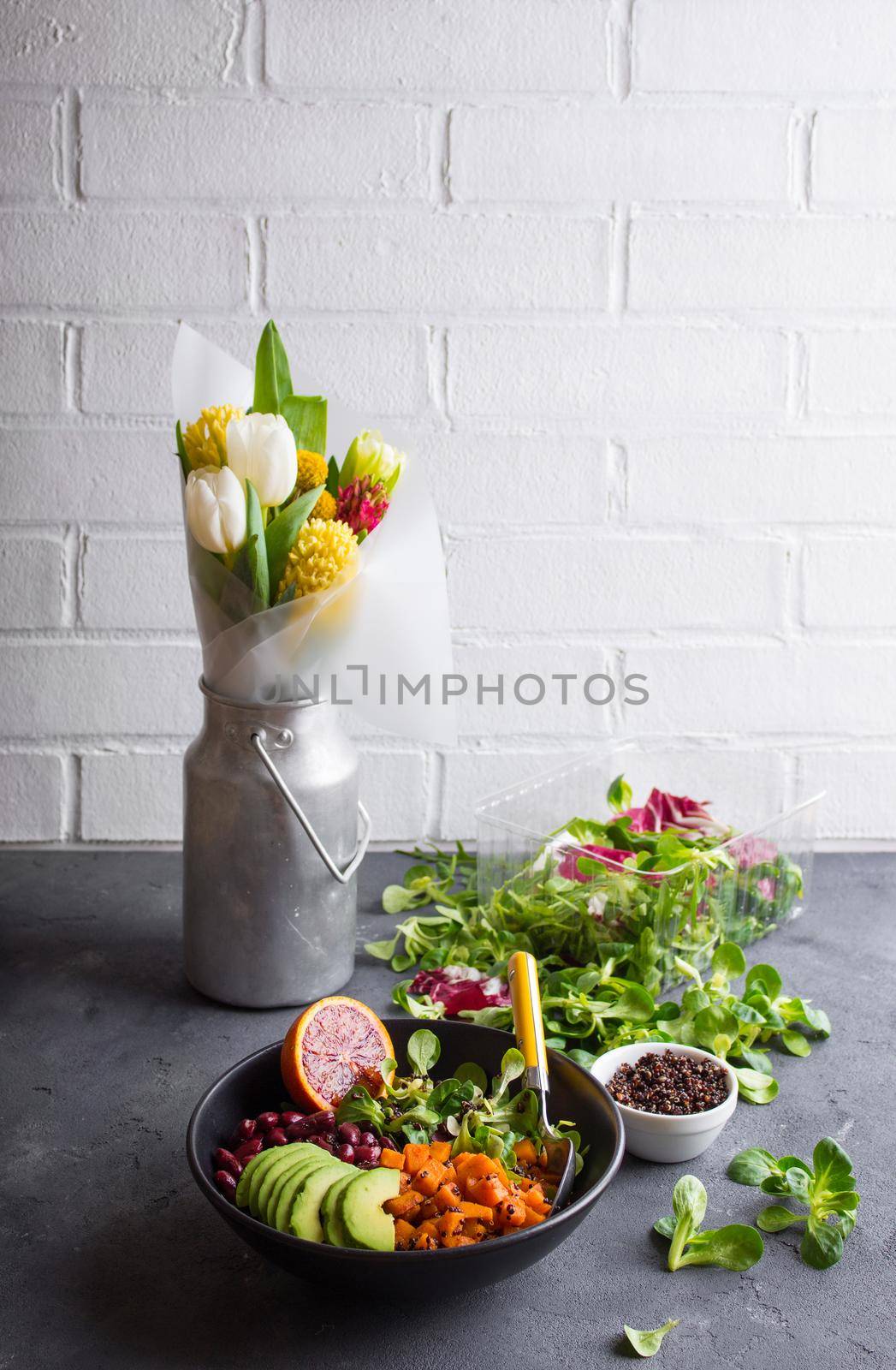 Table with fresh clean organic food. Quinoa vegetables salad bowl, salad leaves, flowers bouquet. Superfood or detox eating concept. Spring setting. Vegan/vegetarian food. Make salad. Space for text