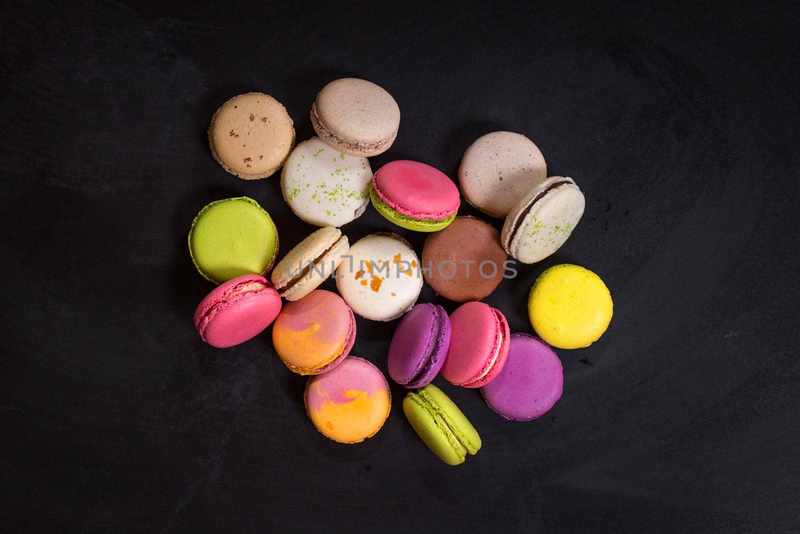 Assorted colorful french cookies macarons on a dark background. Closeup. Concept of the macarons