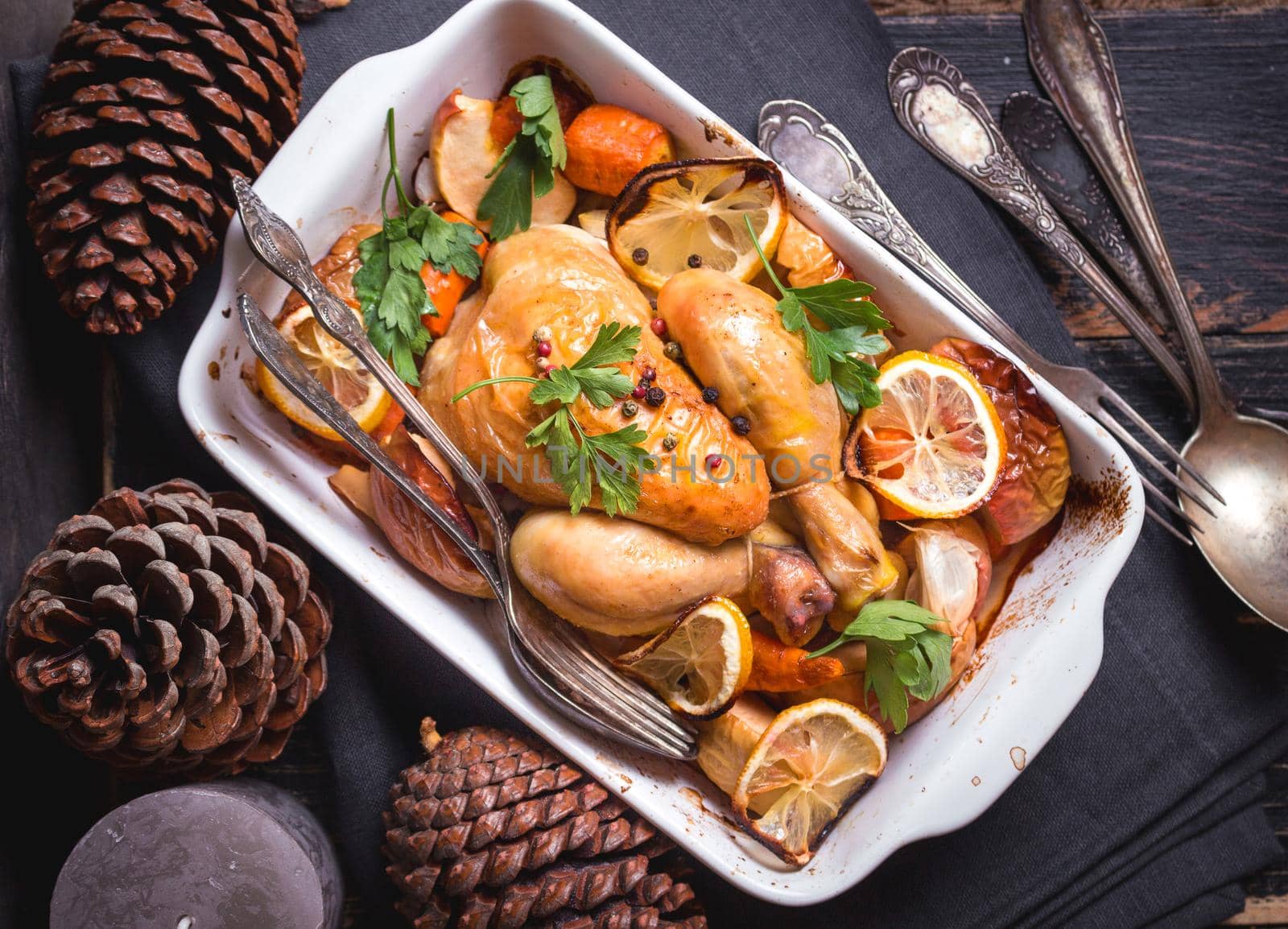 Roasted chicken. Christmas food. Rustic celebration table with roasted chicken, vegetables, apples, decorated with candles, vintage cutlery. Christmas/Thanksgiving dinner. Festive dinner. Top view