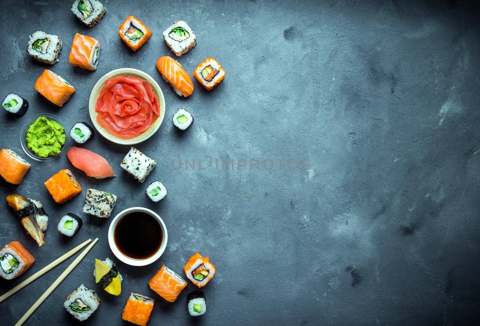 Japanese sushi on a dark background. Sushi rolls, nigiri, maki, pickled ginger, wasabi, soy sauce. Sushi set on a table. Space for text. Top view. Sushi background. Asian or Japanese food frame. Toned