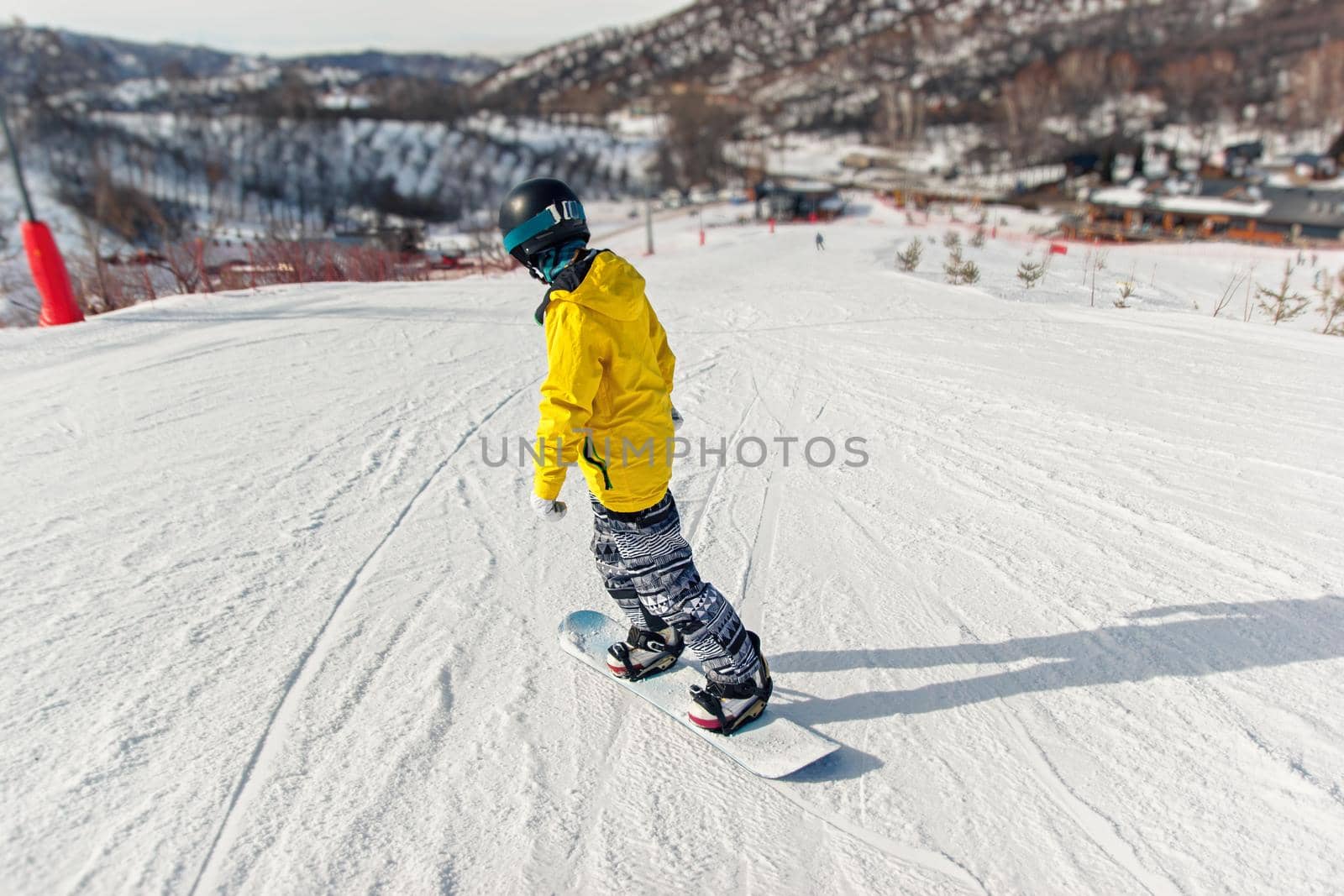 Snowboarder in black helmet, yellow jacket learns to snowboard technique on the ski slope