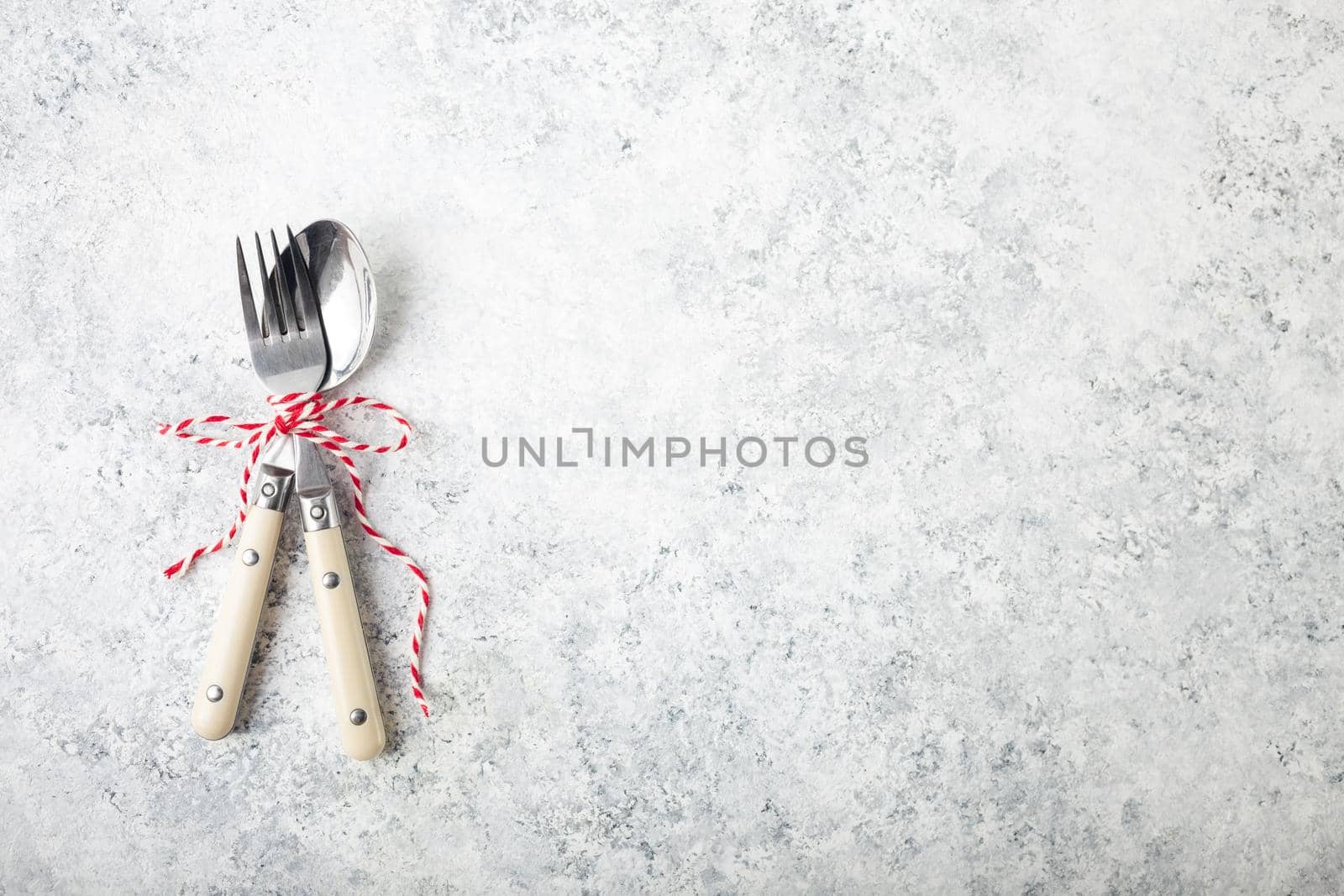 Christmas/New Year background. Christmas table place setting. Festive dinner background. Spoon, fork, white concrete background. Christmas decoration. Space for text. Top view. Holidays. Greeting card