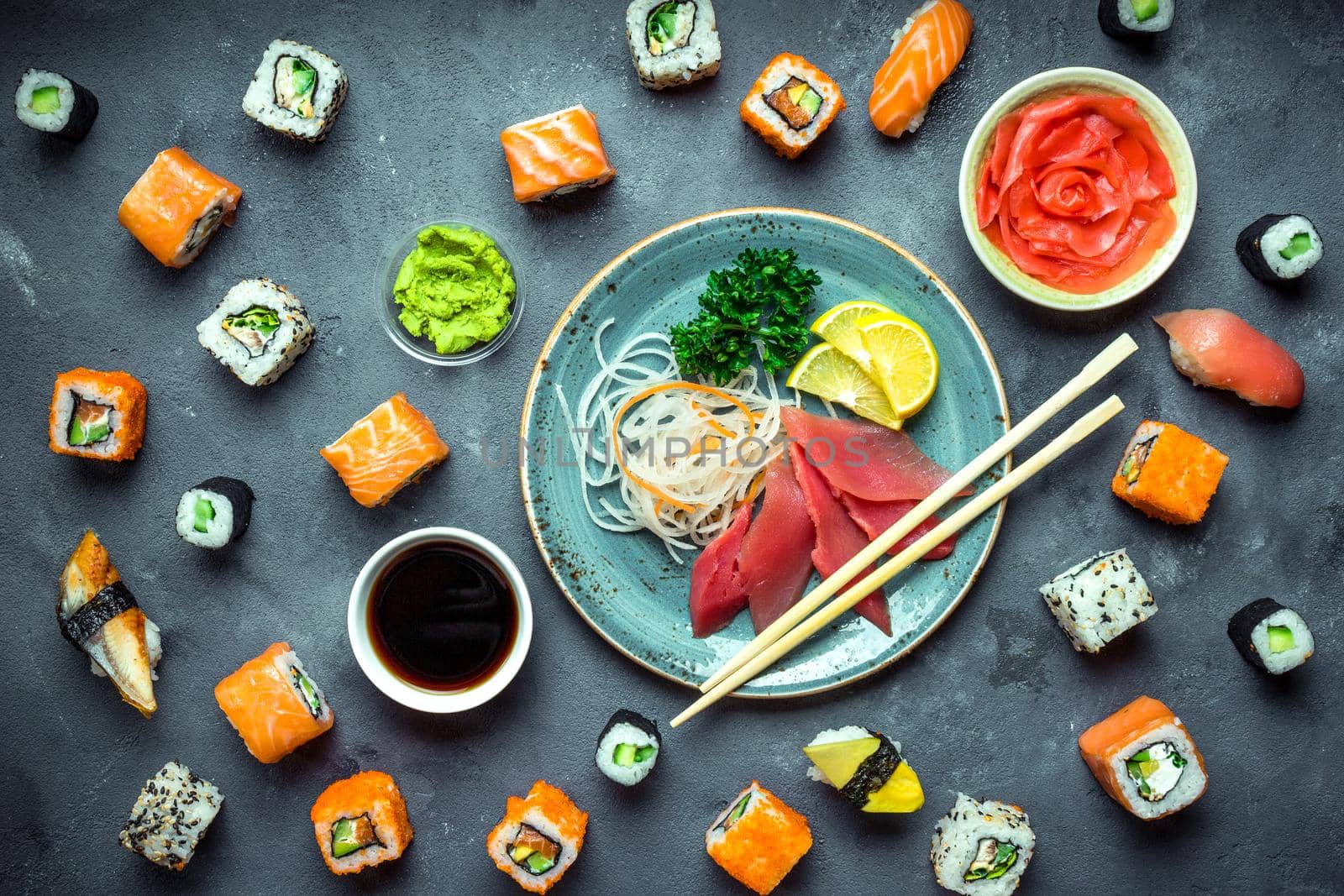Japanese sushi on rustic dark background. Sushi rolls, sashimi, nigiri, maki, pickled ginger, wasabi, soy sauce. Sushi set on a table. Top view. Asian or Japanese food. Sushi restaurant concept. Toned
