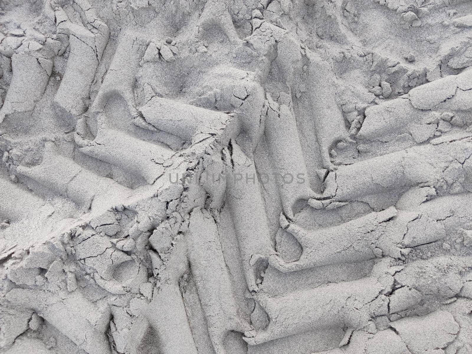 Textured pattern of car tires on gray sand, top view. Close-up