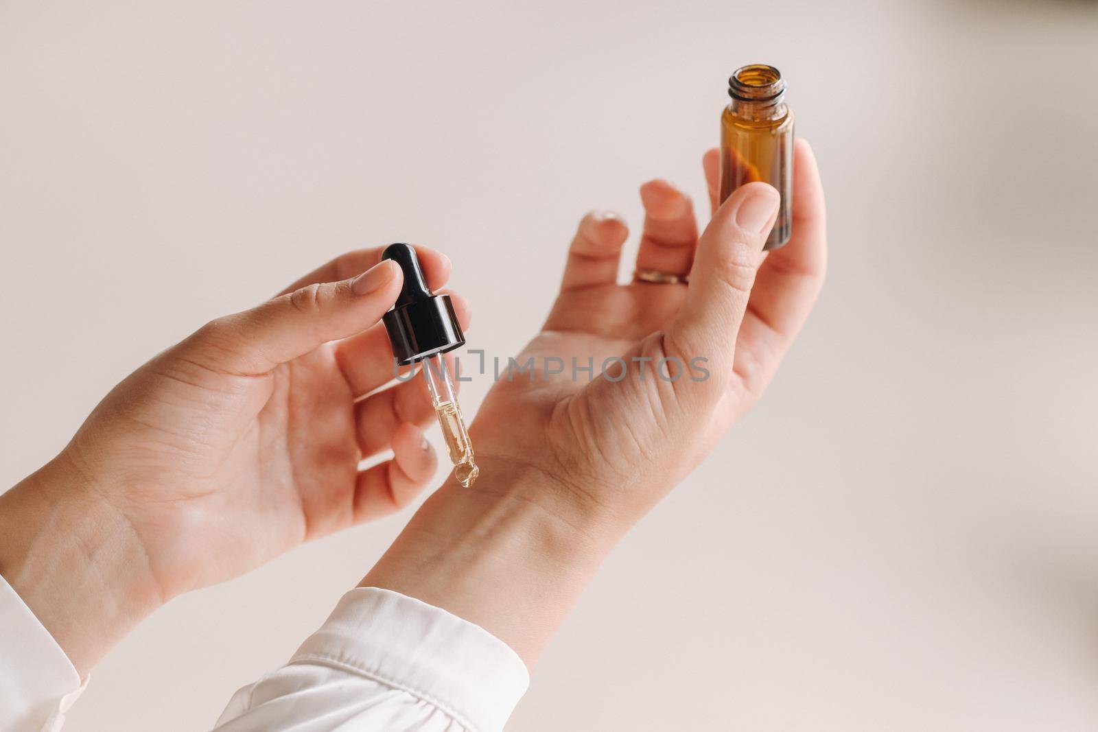 Close-up of a Woman's hands applying essential oil on her wrist indoors.