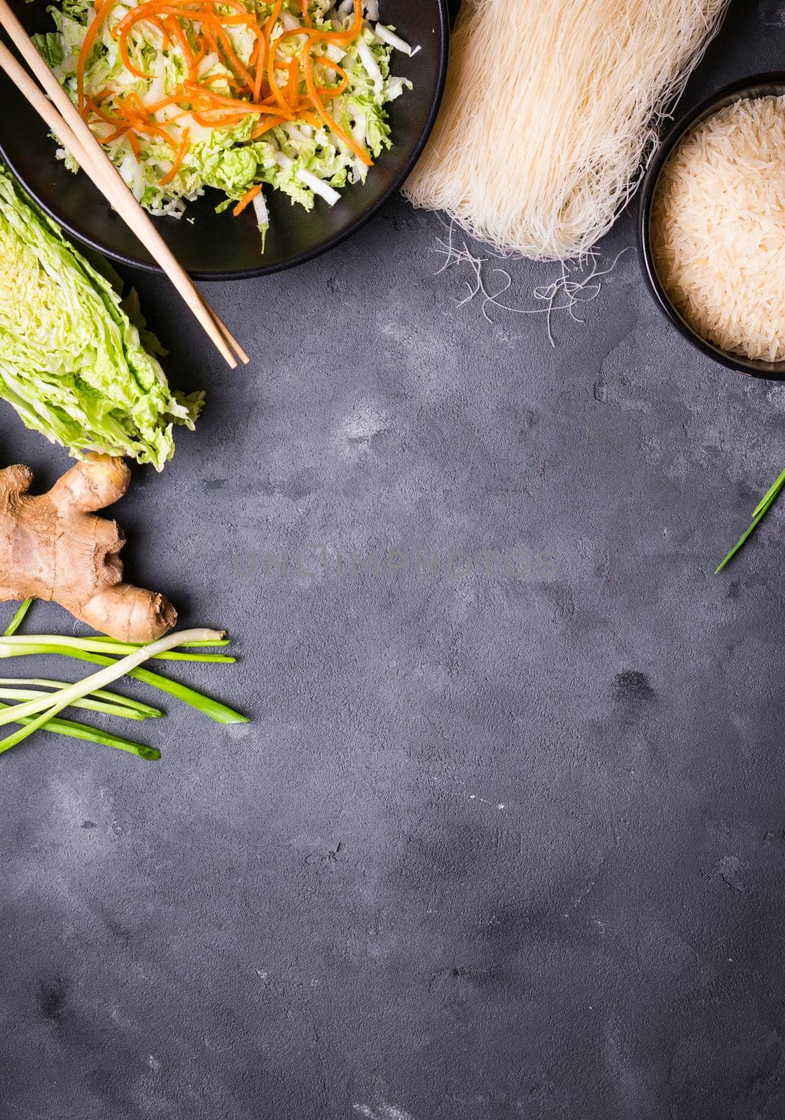 Ingredients for making chinese dinner: rice noodles, rice, napa cabbage, ginger, green onion. Asian cooking ingredients. Top view. Preparing healthy asian meal with vegetable salad. Space for text