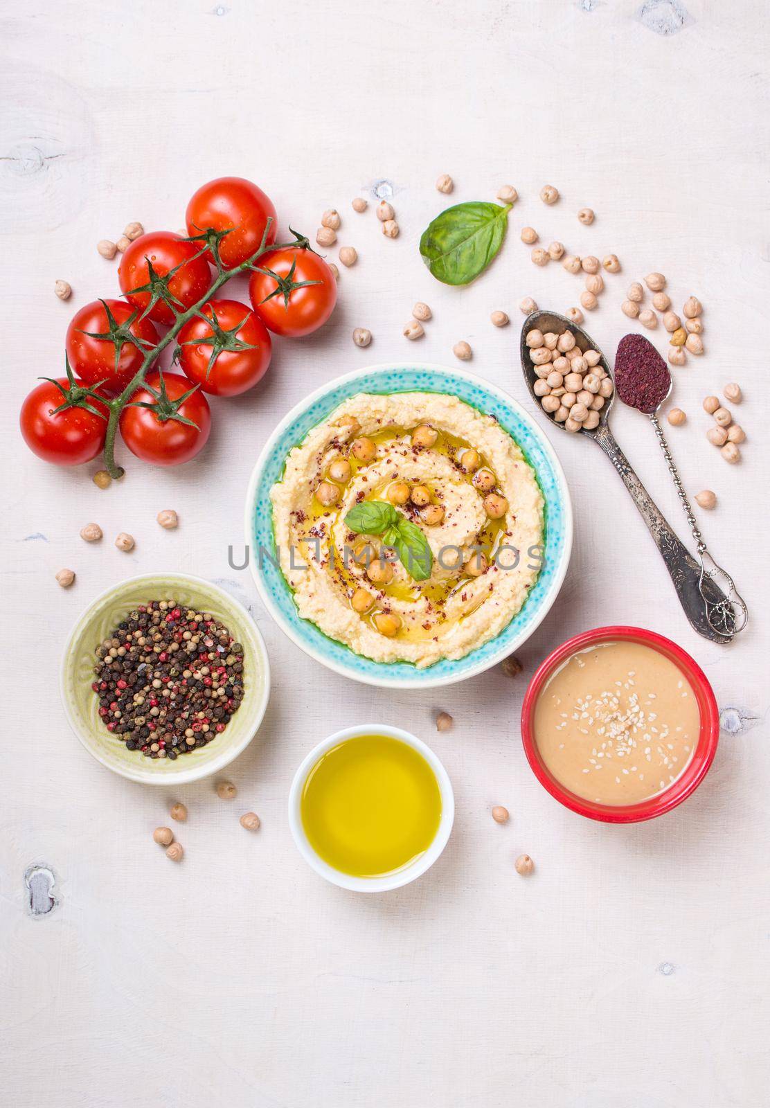 Hummus ingredients. Chickpea, tahini paste, olive oil, sesame seeds, sumac, herbs on white rustic wooden background. Set of raw ingredients for making hummus. Middle eastern cuisine. Top view