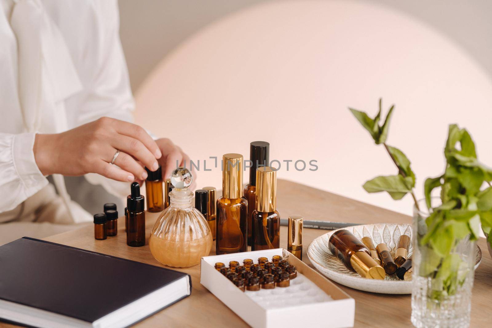 Close-up of a Woman's hands applying essential oil on her wrist indoors.