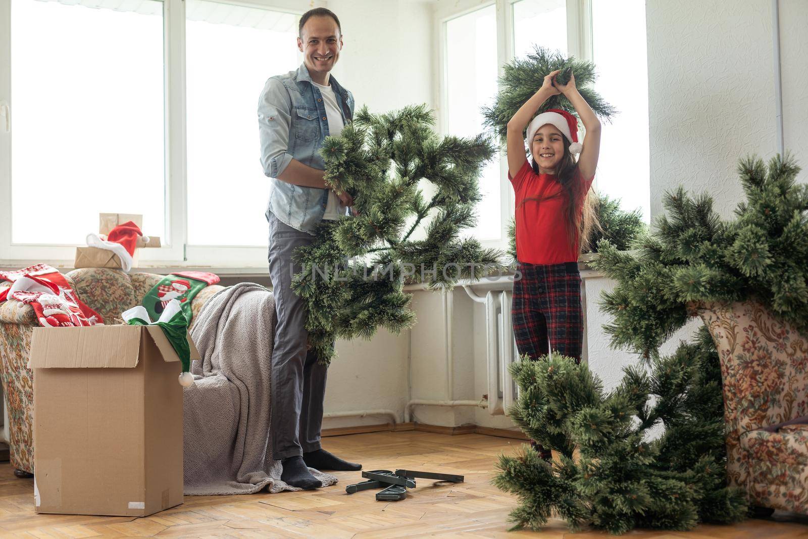 father and daughter install an artificial Christmas tree.