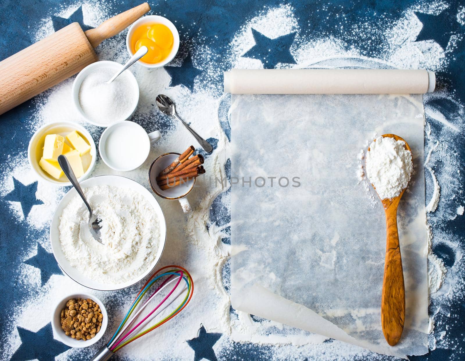 Baking background. Flour, sugar, eggs, butter, milk, cinnamon sticks, whisk, rolling pin, baking paper. Space for text. Ingredients for baking. Kitchen utensils. Top view. Making baked goods. Concept