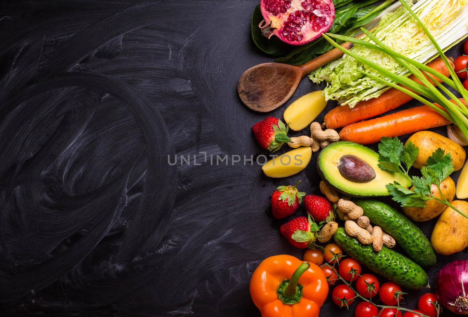 Vegetables, fruits, herbs, raw ingredients for cooking and spoon on rustic black chalk board background. Healthy, clean eating concept. Vegan or gluten free diet. Space for text. Top view. Food frame