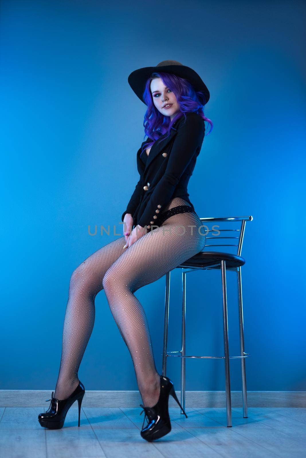 the sexy girl in a fashionable jacket and hat poses erotically in her underwear
