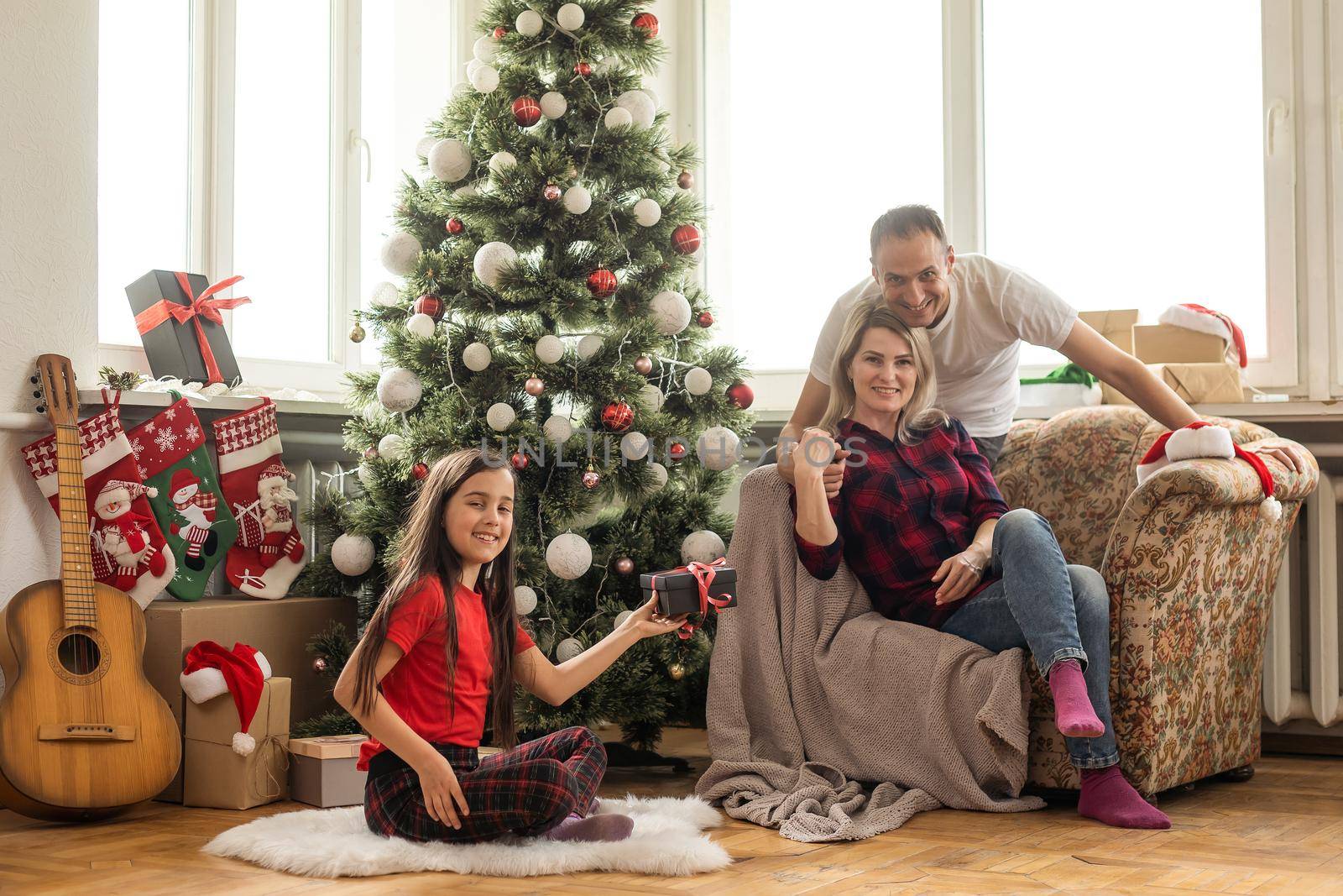 Christmas family. Happy mom, dad and little daughter. Enjoyng love hugs, holidays people. Togetherness concept.