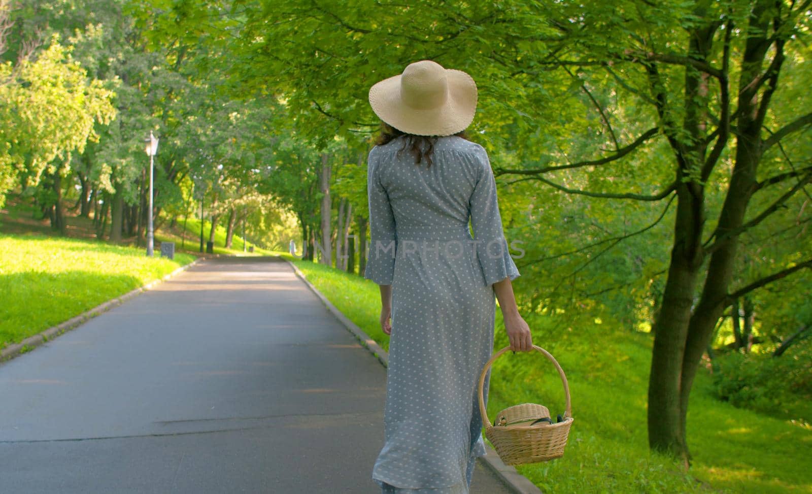 Romantic woman walking in the park. Rear view by Chudakov