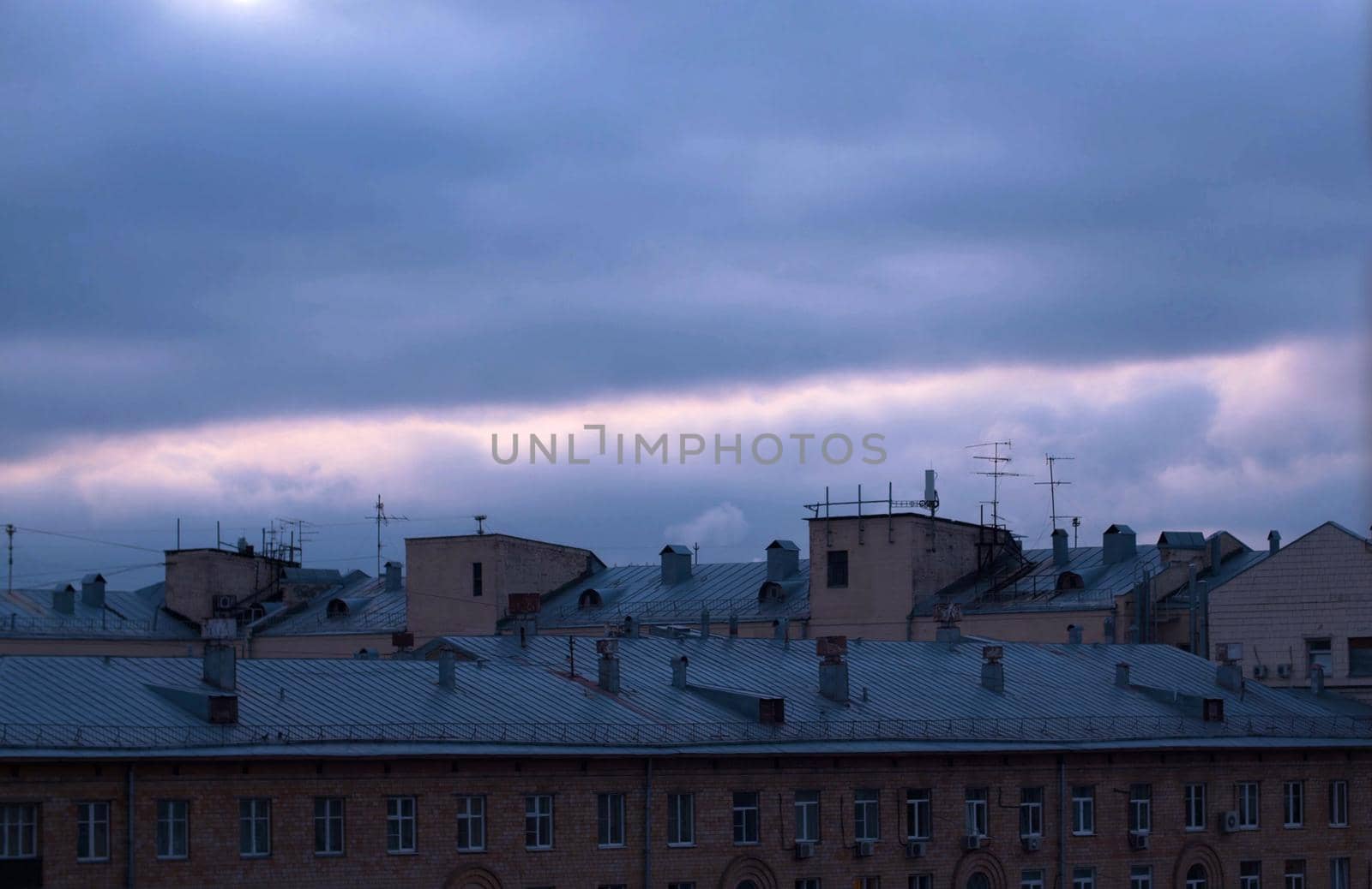 Dark cloudy sky over city buildings by Chudakov