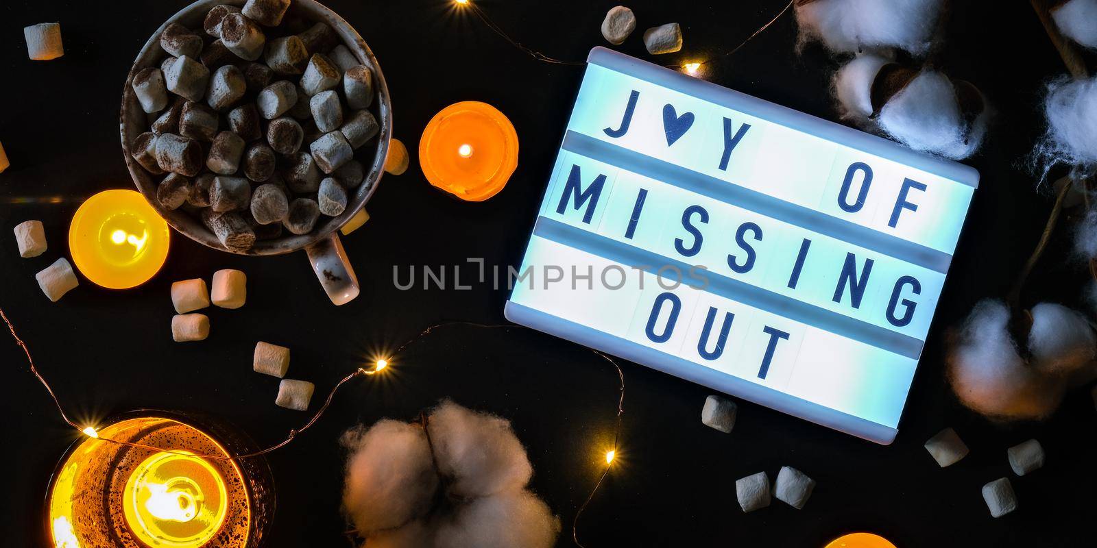 Lightbox with text JOMO Joy of Missing Out. The concept of relaxation from information and gadgets. Top view. Flat lay. Cup with cacao and marshmallows. Digital detox