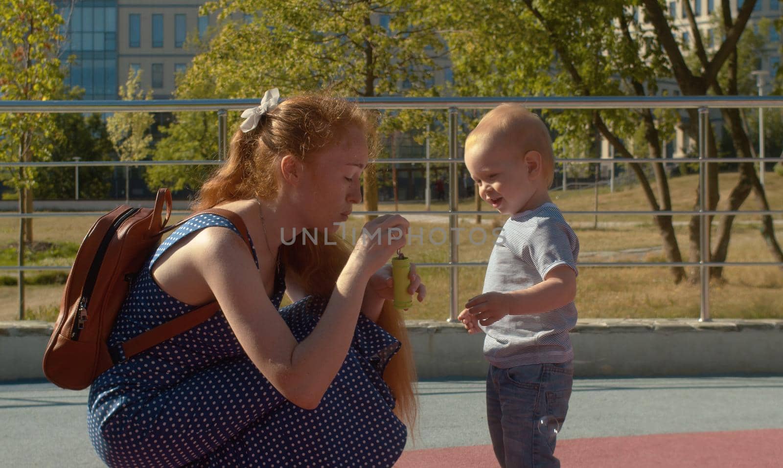 Mom blows soap bubbles in the park by Chudakov