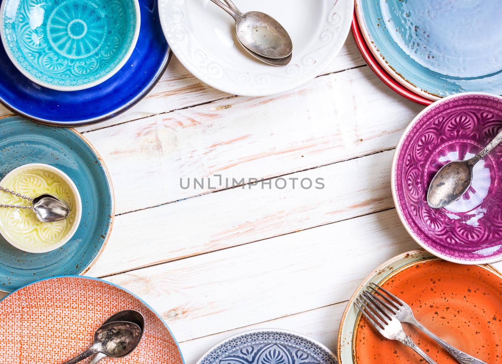 Vintage multicolored empty plates and bowls on a gray linen tablecloth. With antique spoons and forks. Space for text. Table setting. Shabby chic/retro style. Top view. Rustic kitchen. Copy space