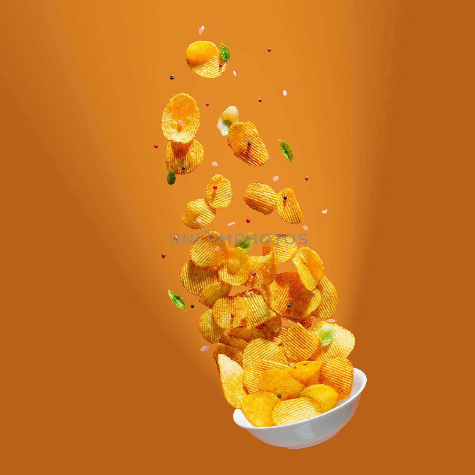 Potato chips falling onto plate on white background. Advertising concept. Levitation flying chips by PhotoTime