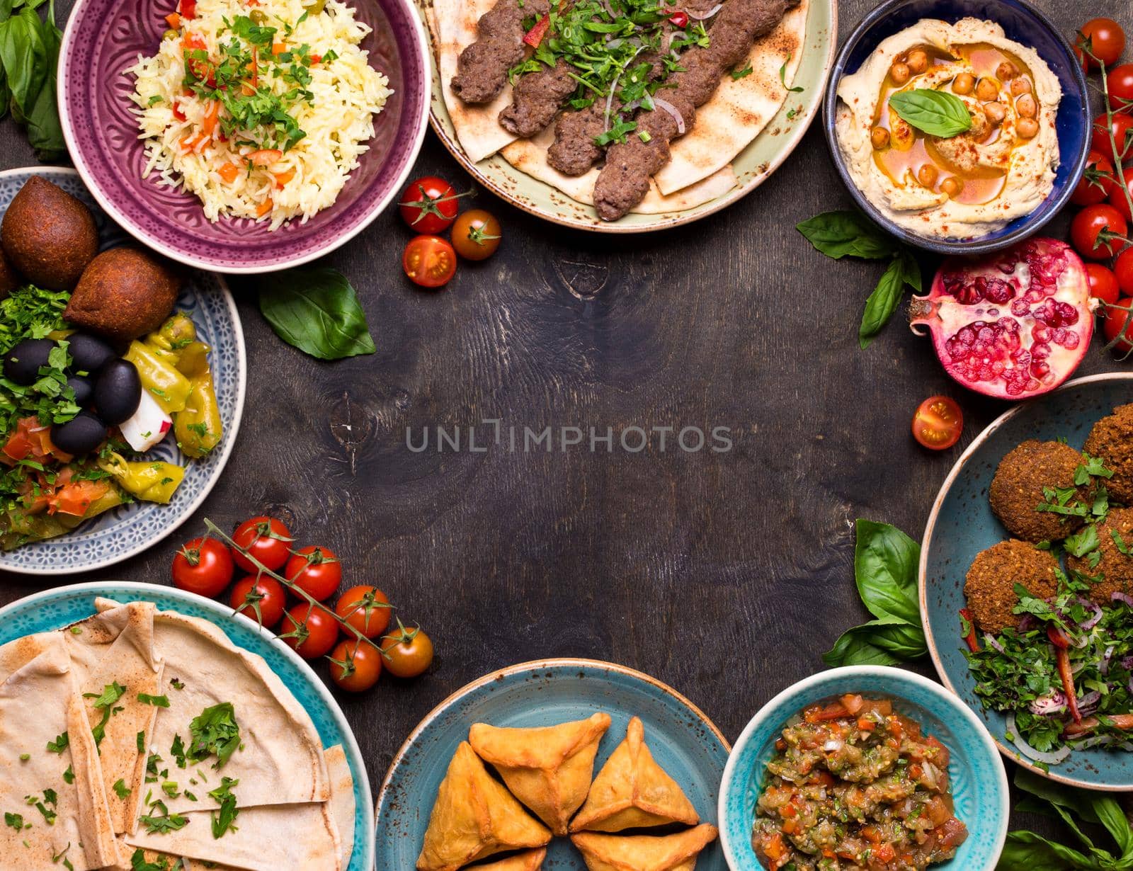 Middle eastern or arabic dishes and assorted meze on a dark background. Meat kebab, falafel, baba ghanoush, hummus, rice with vegetables, sambusak, kibbeh, pita. Halal food. Space for text. Top view