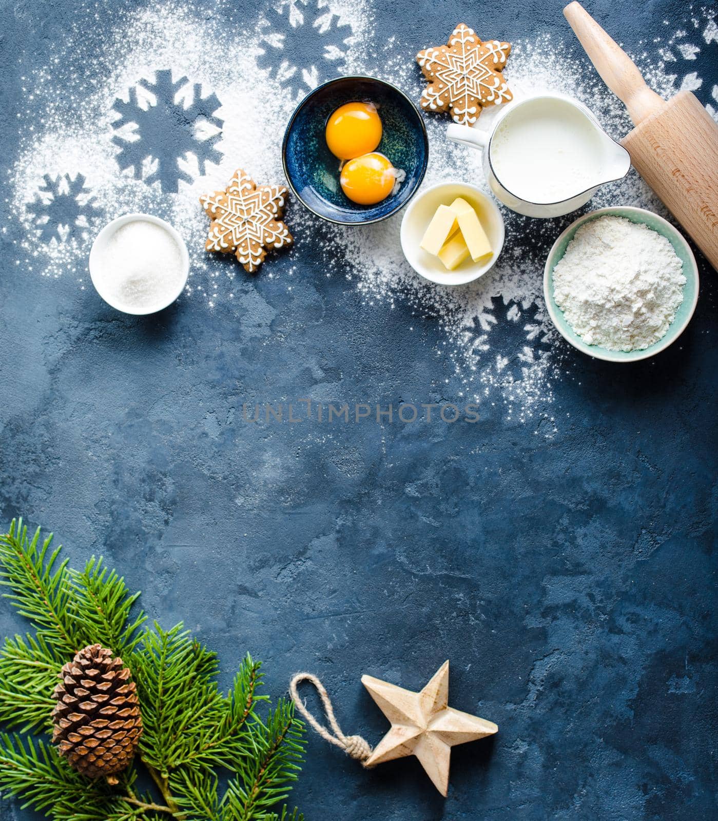 Christmas/New Year food background. Baking ingredients, snowflake cookies, Christmas decoration. Making festive New Year sweets. Flour, rolling pin, gingerbread, milk, eggs. Space for text. Top view