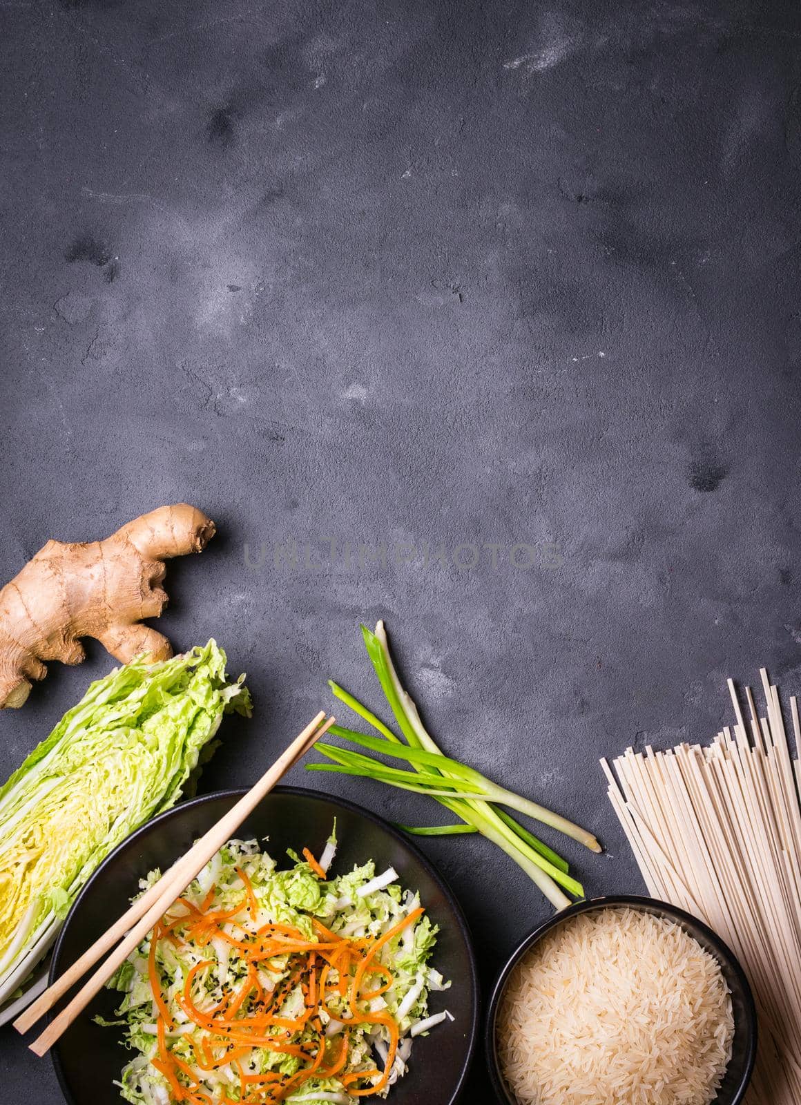 Ingredients for making chinese dinner: wheat noodles, rice, napa cabbage, ginger, green onion. Asian cooking ingredients. Top view. Preparing healthy asian meal with vegetable salad. Space for text