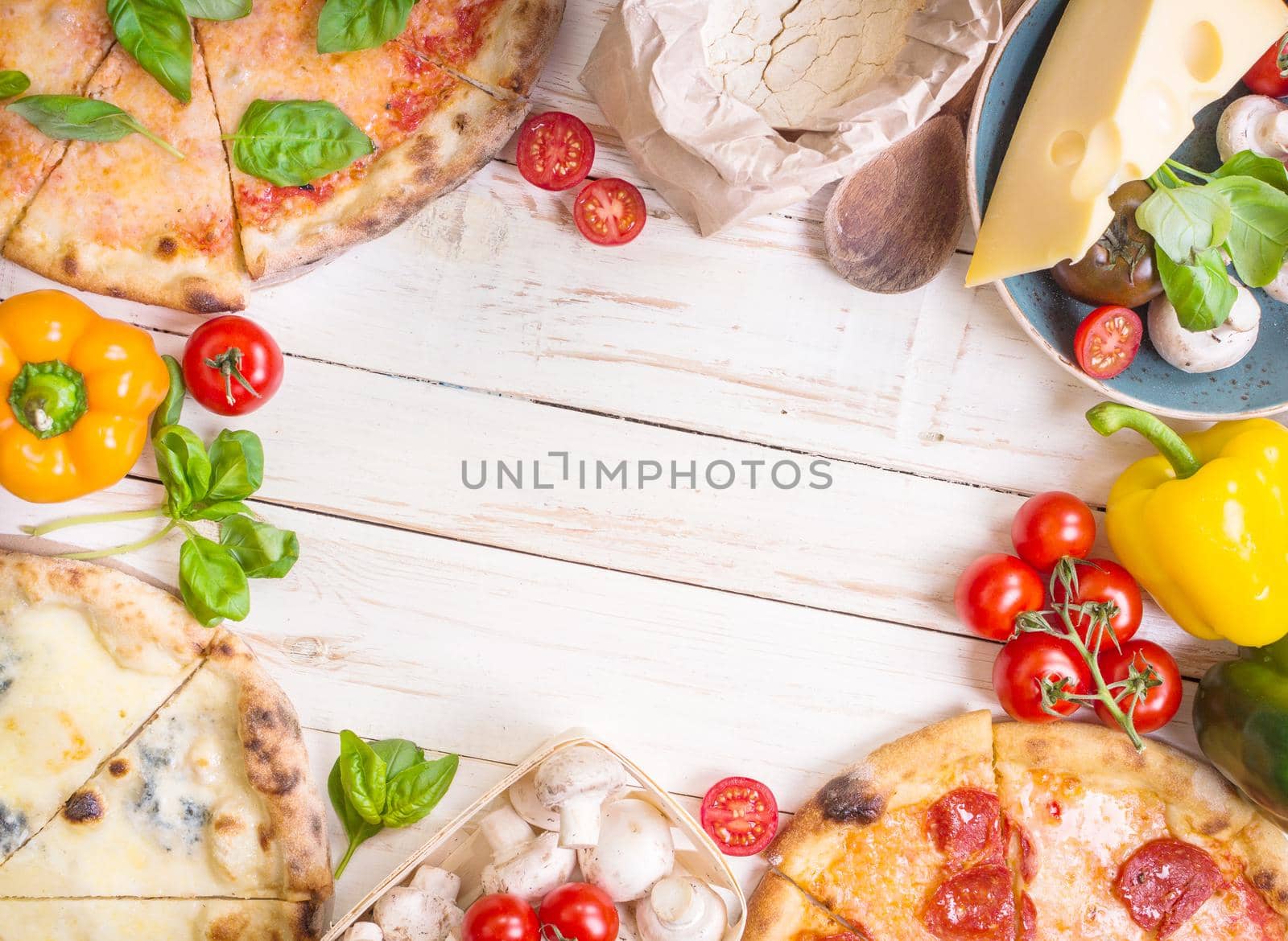 Pizza with assorted toppings and ingredients background. Space for text. Pizza, flour, cheese, tomatoes, basil, pepperoni, mushrooms and rolling pin over white wooden background. Top view. Food frame