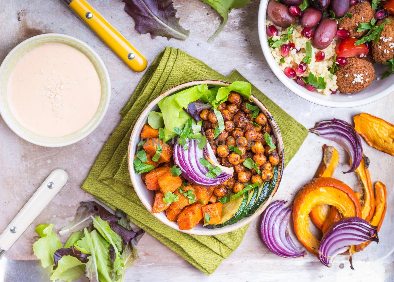 Healthy vegetarian salads with vegetables, sweet potato, falafel, bulgur. Healthy buddha bowl salads, sauce. Vegan/vegetarian food. Healthy lunch/dinner. Salad in bowl on table. Top view. Ingredients