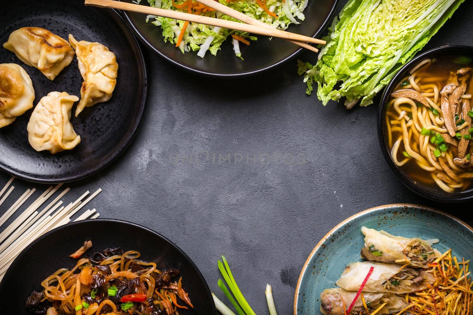 Chinese food dark background. Chinese noodles, fried rice, noodle soup, dim sum, spring rolls, salad. Traditional Chinese cuisine dishes set. Space for text. Top view. Chinese restaurant concept