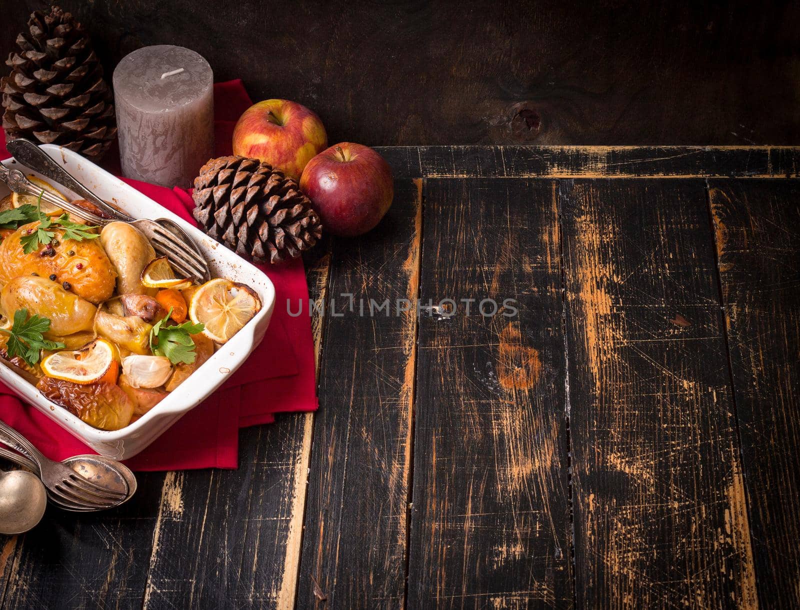 Roasted chicken. Christmas food background. Rustic celebration table with roasted chicken, vegetables, apples, decorated with candles, vintage cutlery. Christmas/Thanksgiving dinner. Space for text