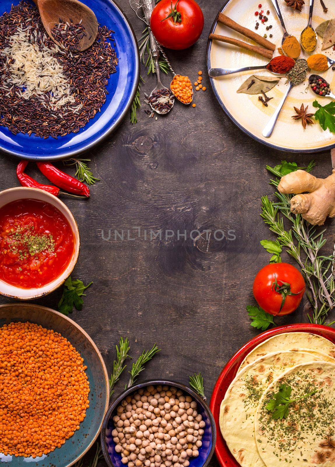 Traditional for asian or eastern cuisine cereal grains, beans, spices on colorful plates/Lentil, rice, chick-pea, tomato chutney, pita. Ingredients for indian or eastern food background/Space for text