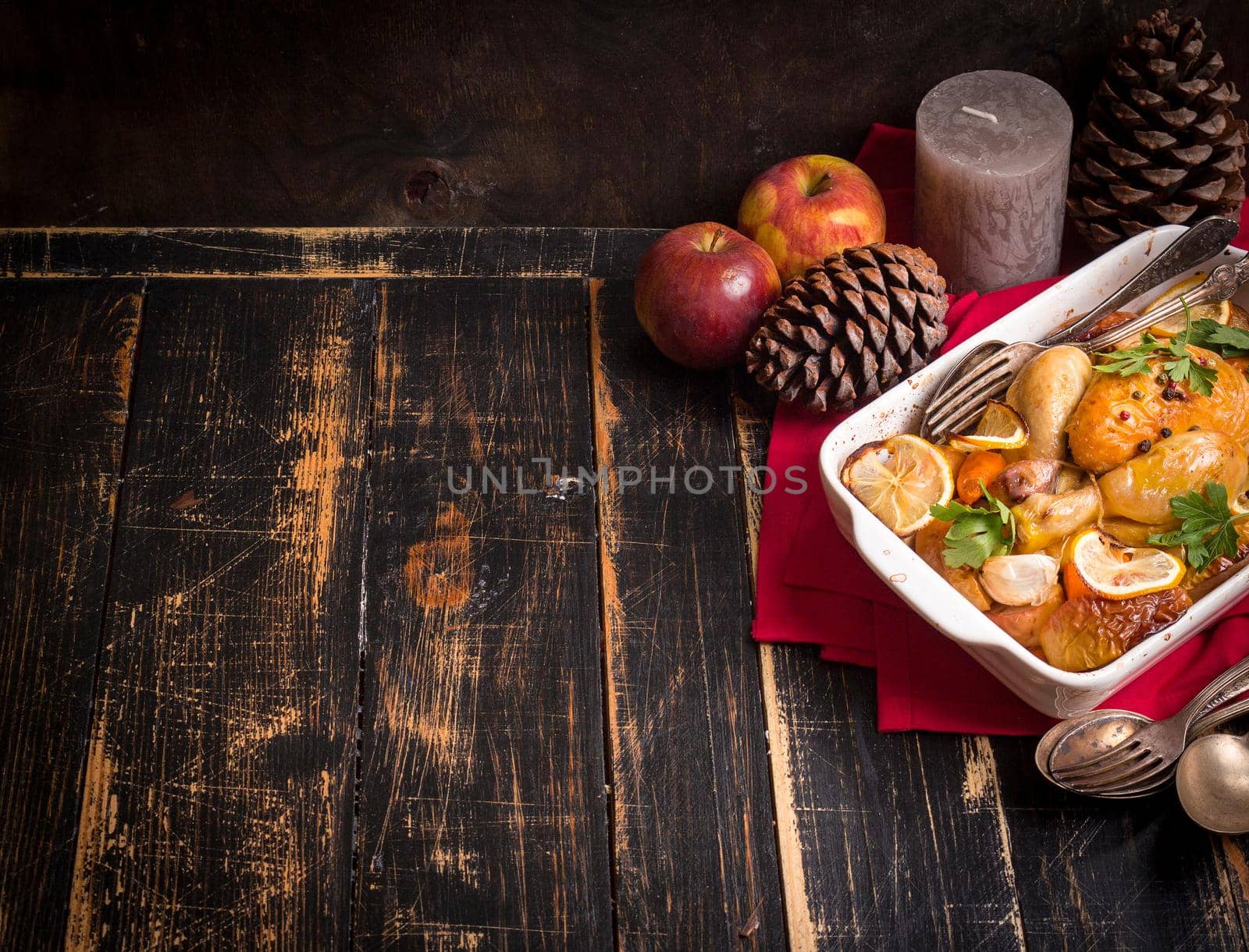Roasted chicken. Christmas food background. Rustic celebration table with roasted chicken, vegetables, apples, decorated with candles, vintage cutlery. Christmas/Thanksgiving dinner. Space for text