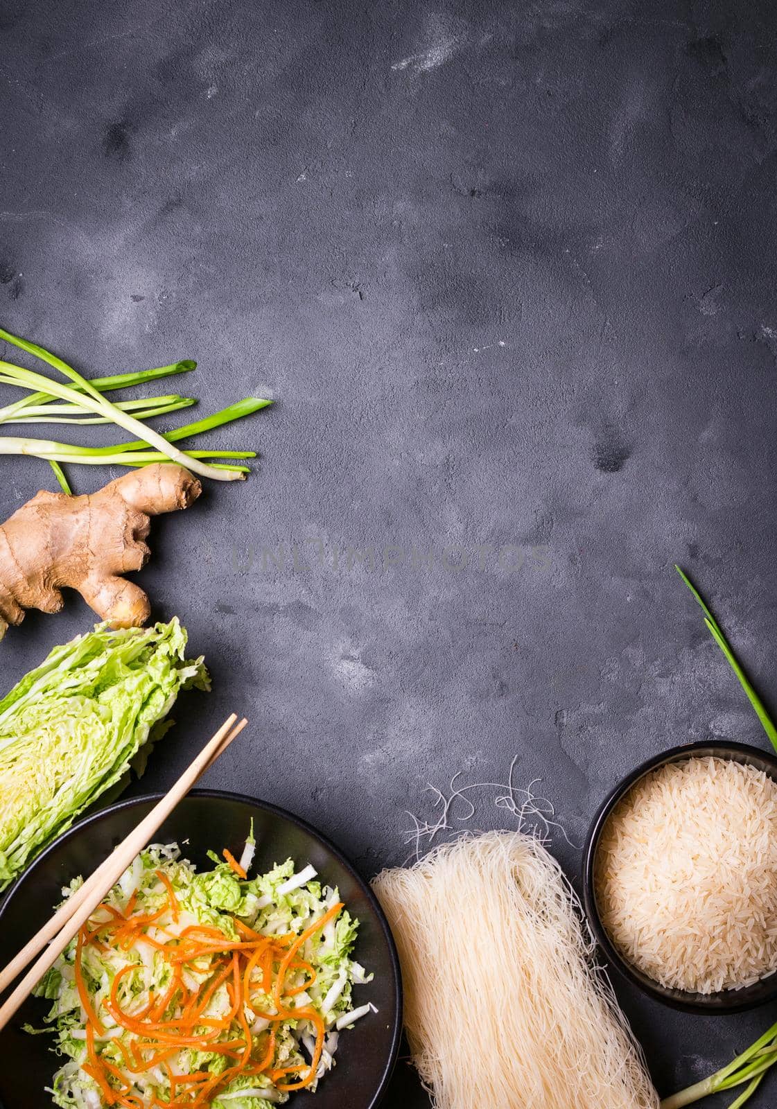 Ingredients for making chinese dinner: rice noodles, rice, napa cabbage, ginger, green onion. Asian cooking ingredients. Top view. Preparing healthy asian meal with vegetable salad. Space for text