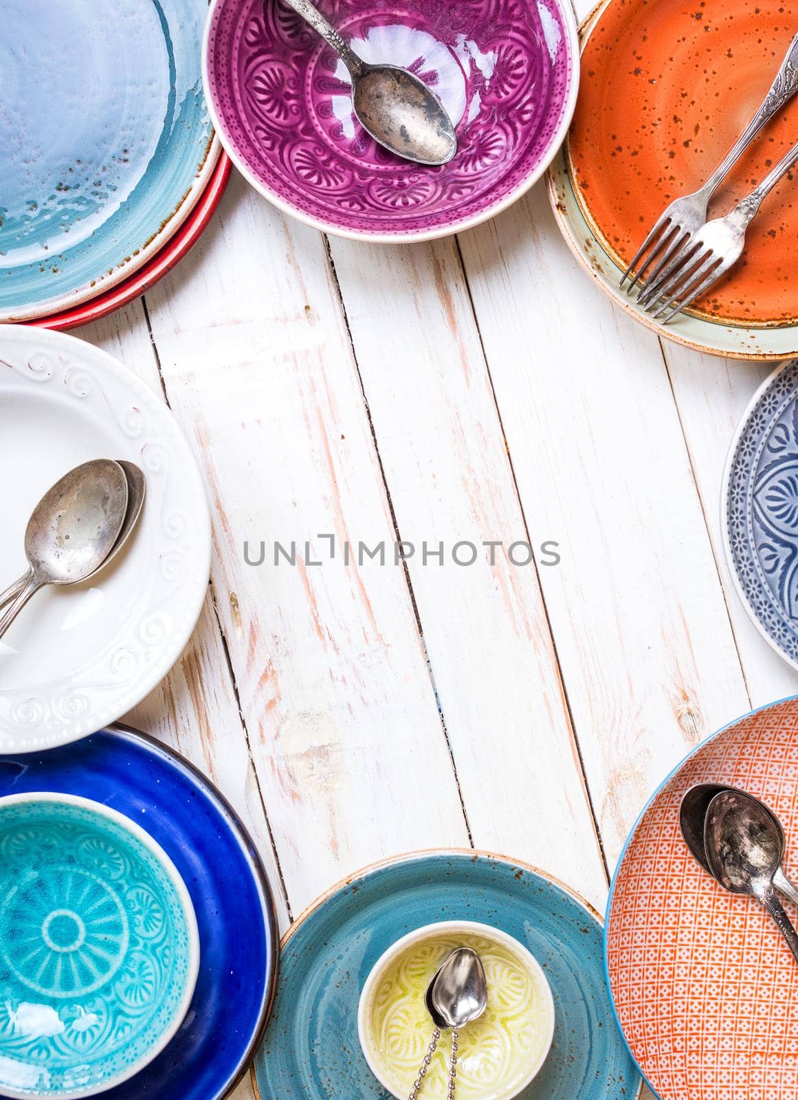 Vintage multicolored empty plates and bowls on a gray linen tablecloth. With antique spoons and forks. Space for text. Table setting. Shabby chic/retro style. Top view. Rustic kitchen. Copy space