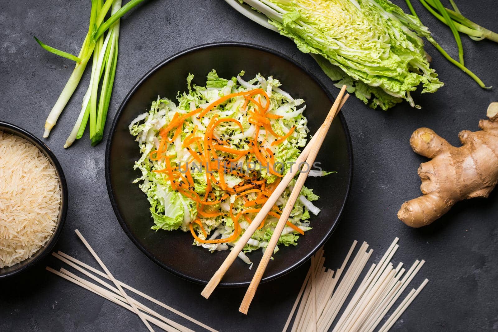 Asian or chinese salad with napa cabbage, carrot, black sesame seeds. Ingredients for making chinese dinner: wheat noodles, rice, napa cabbage, ginger, green onion. Asian cooking ingredients. Top view