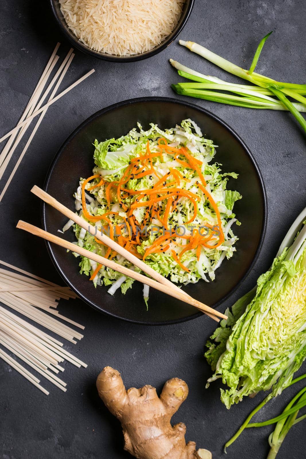 Asian or chinese salad with napa cabbage, carrot, black sesame seeds. Ingredients for making chinese dinner: wheat noodles, rice, napa cabbage, ginger, green onion. Asian cooking ingredients. Top view