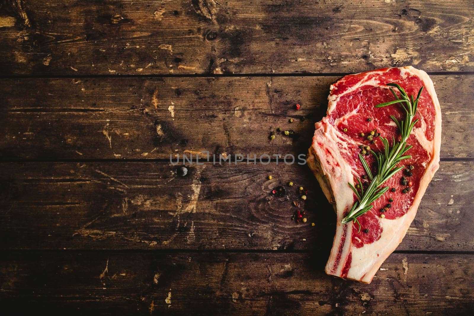 Raw marbled meat steak, pepper, herbs on rustic wooden background. Space for text. Beef Rib eye steak ready for cooking. Top view. Copy space. Ingredients for meat roasting. Ribeye meat steak. Closeup