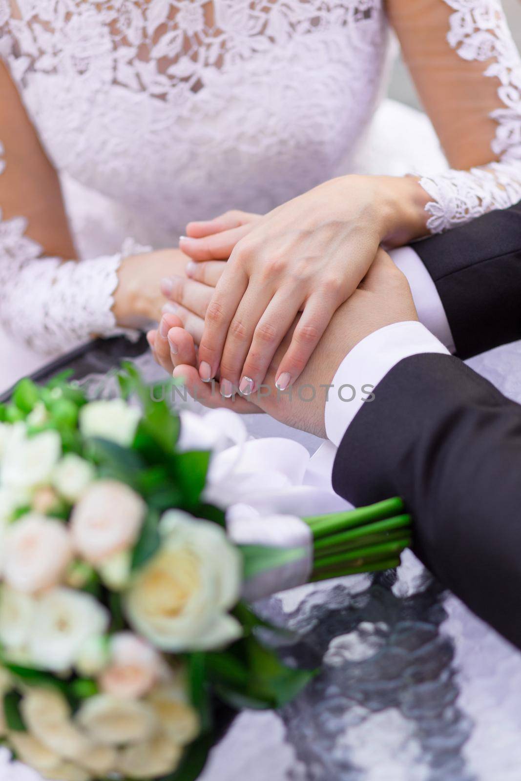 Close-up of wedding hands and bouquet lie on the table