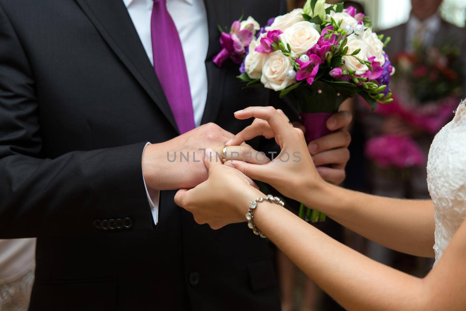 Bride putting a ring on groom's finger during wedding ceremony