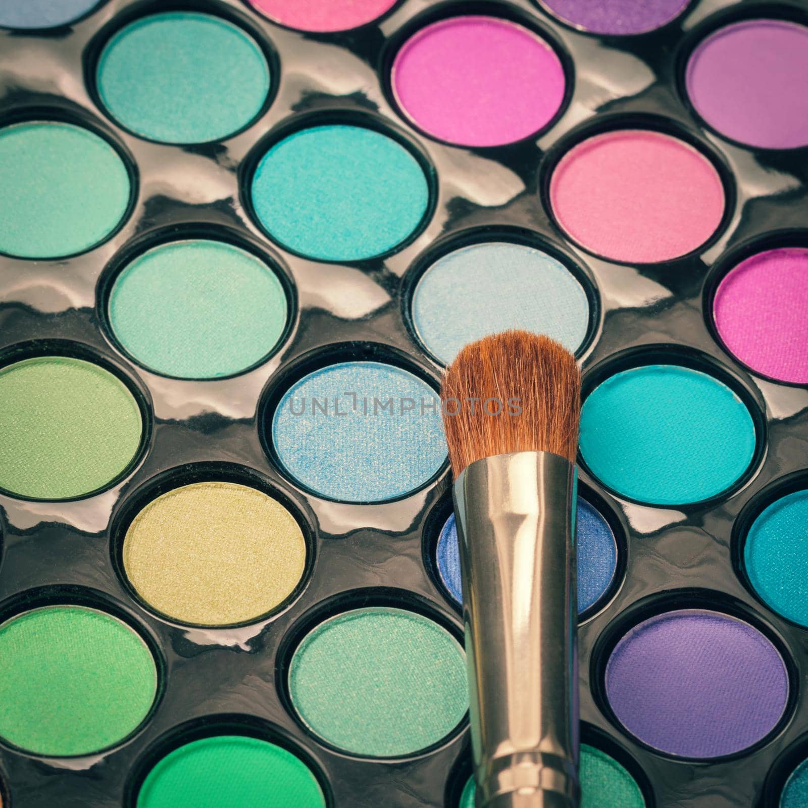 Flat lay of makeup brush with colorful makeup palette