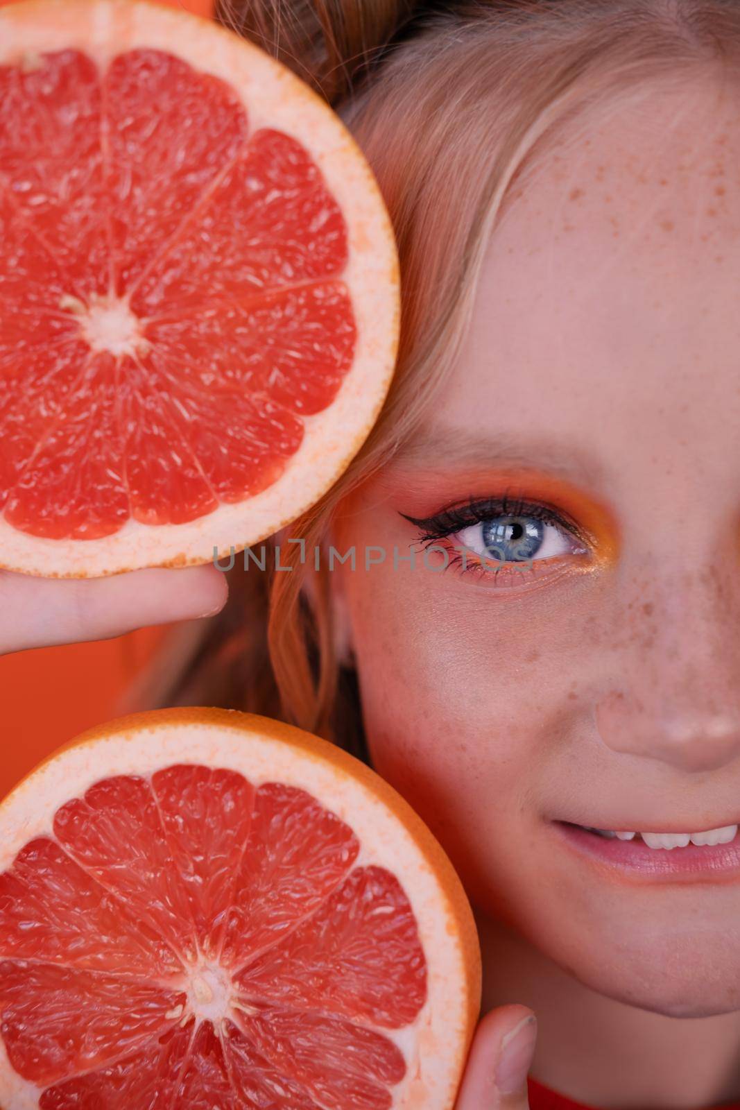 sweet joyful brunette woman girl female with cropped slice of grapefruit near skin face on orange background. tasty juicy fruit. Tropical citrus fruits, Healthy food. weight loss by oliavesna